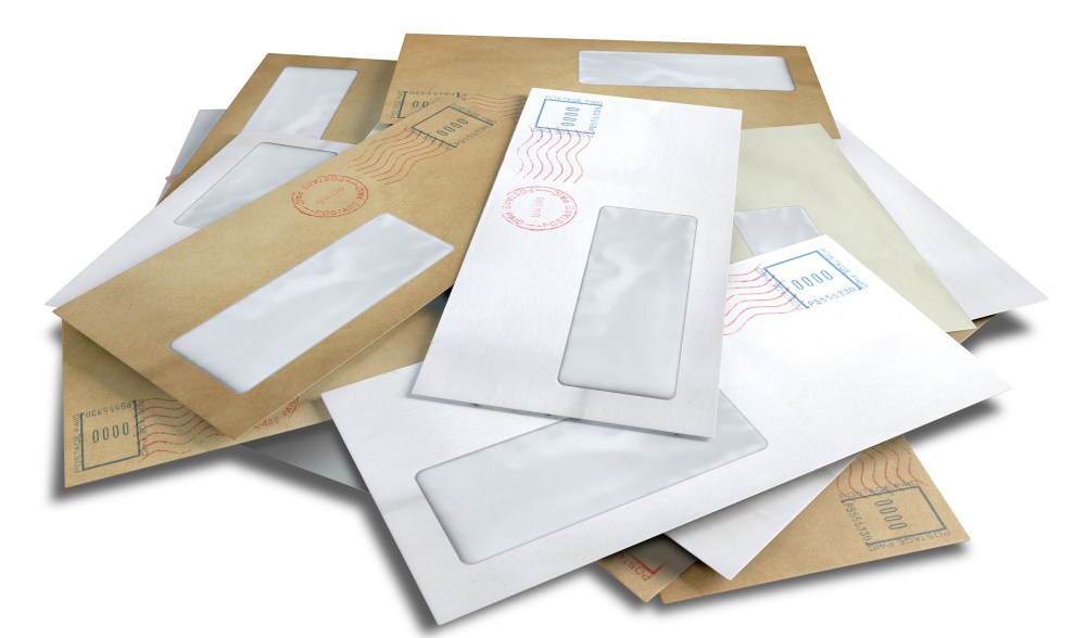 A scattered stack of regular envelopes with delivery stamps and a clear window on an isolated white background